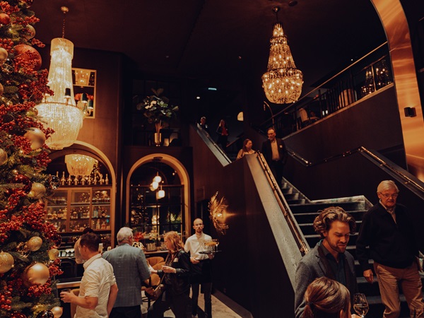 Interieur van TheaterHotel De Oranjerie in Roermond met gasten bij de bar en trap, sfeervol ingericht voor zakelijke bijeenkomsten en diners.