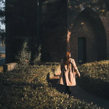 Vrouw wandelt ontspannen langs de Rattentoren in Roermond, omgeven door warme herfstkleuren.