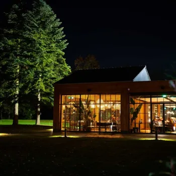 Verlicht gebouw van Hotel Laurabos in de avond, omringd door bomen en bos.